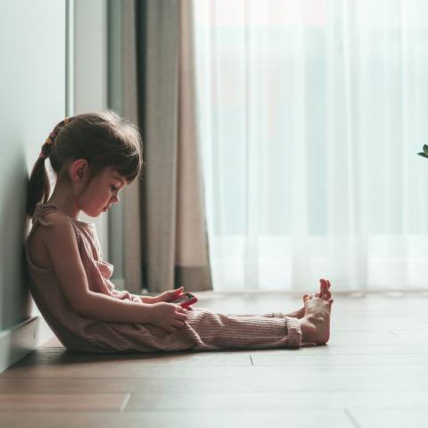 Little girl sitting on a floor looking at the red phone