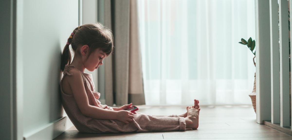 Little girl sitting on a floor looking at the red phone